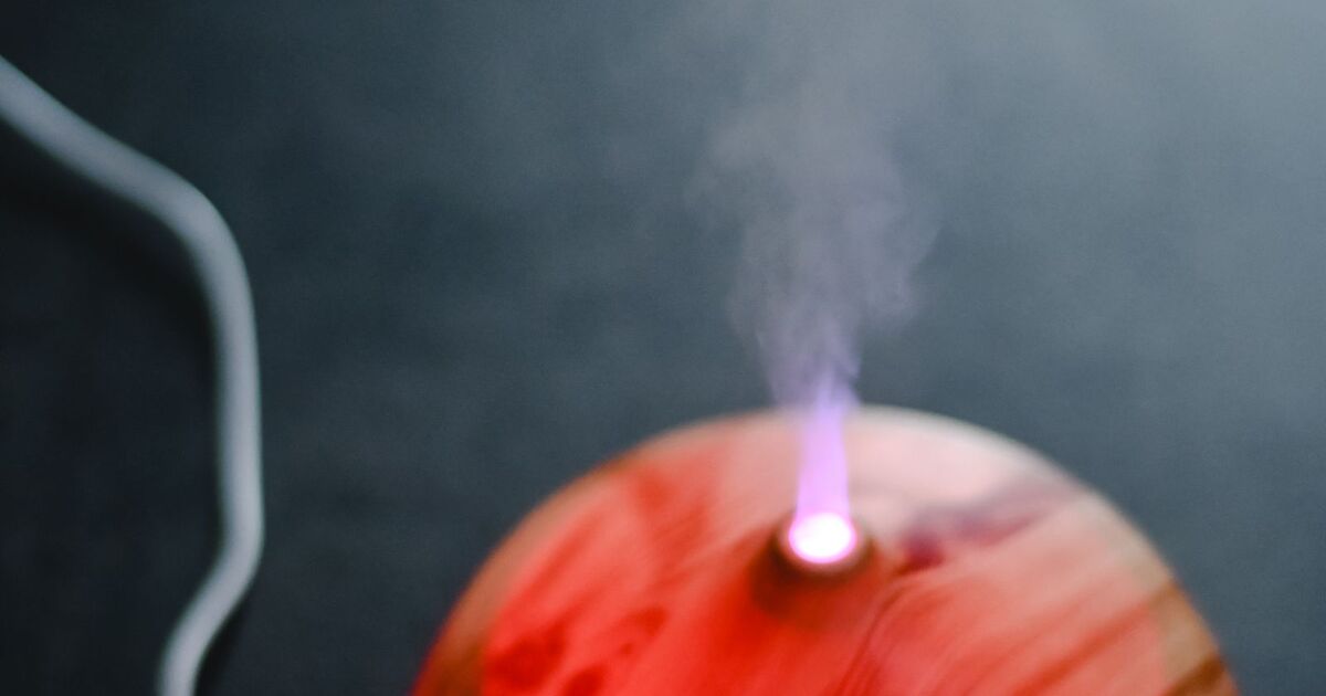 Diffuseur en bois diffusant une brume éclairée d'une lumière rose tamisée, créant une ambiance apaisante en soirée