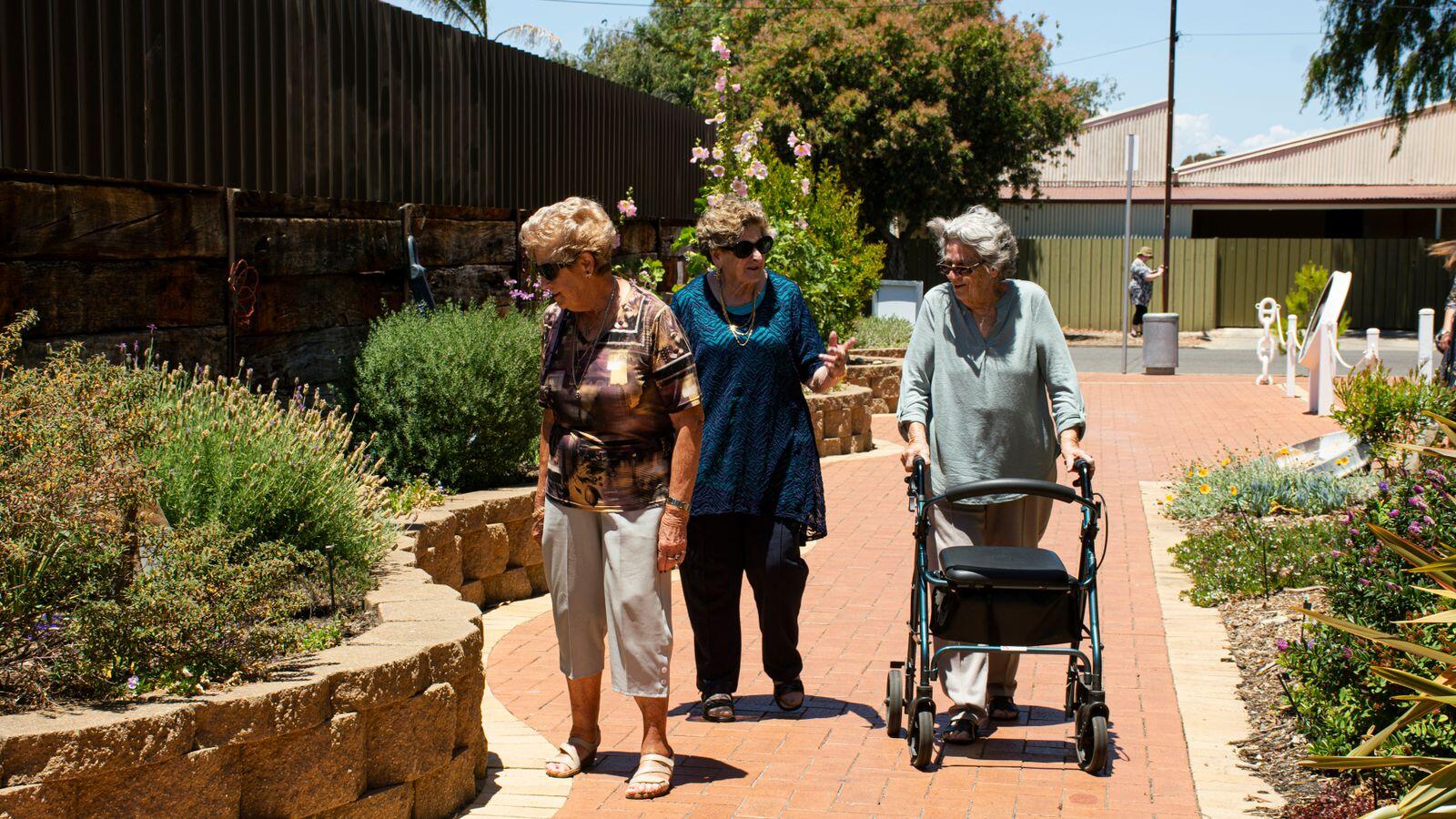 Deux femmes seniors marchent côte à côte dans un parc verdoyant en été